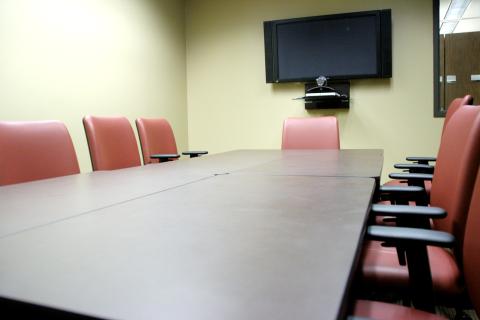 Meeting room with a table, 8 chairs, and a display screen on the wall